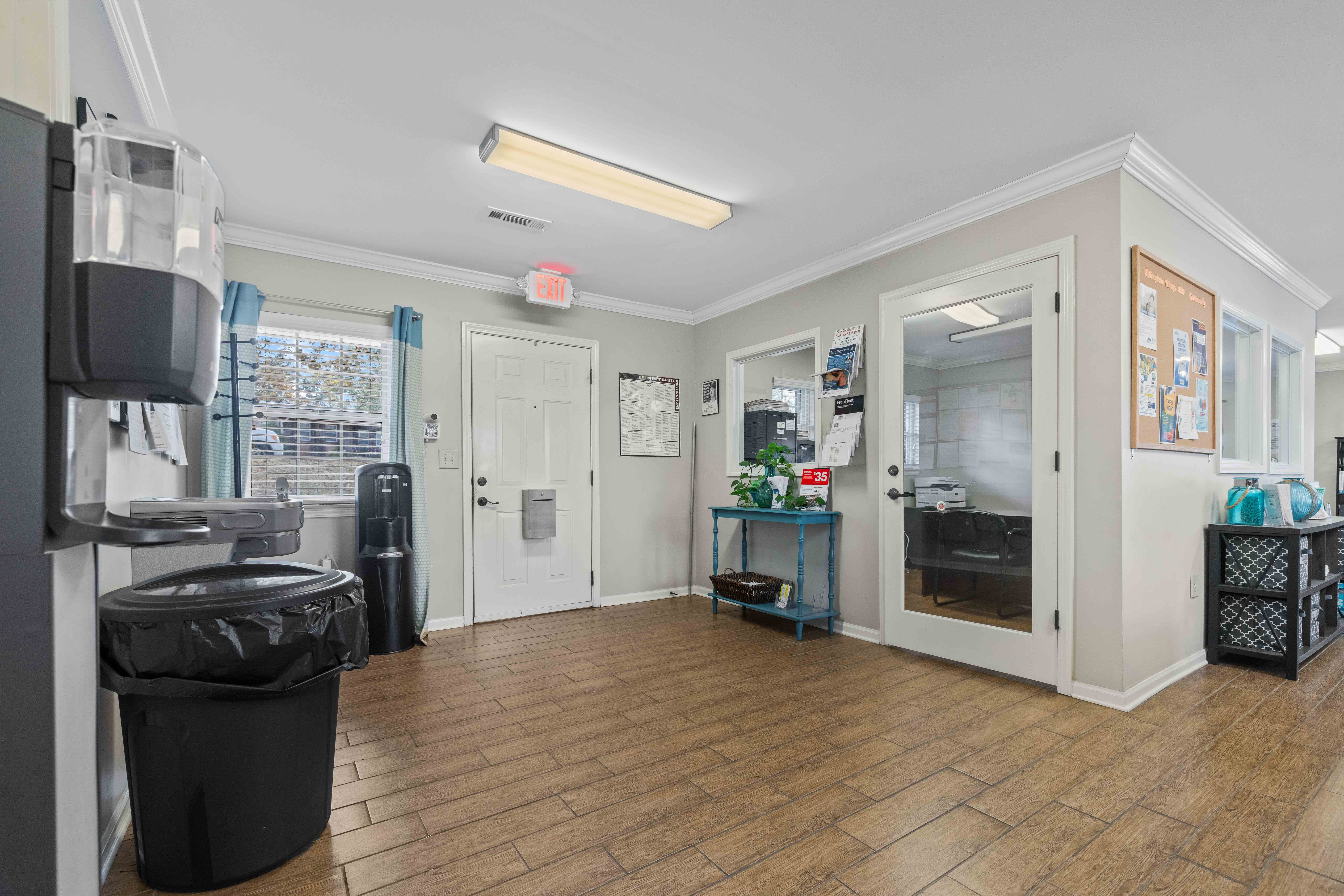 A room with a black trash can and a white door.